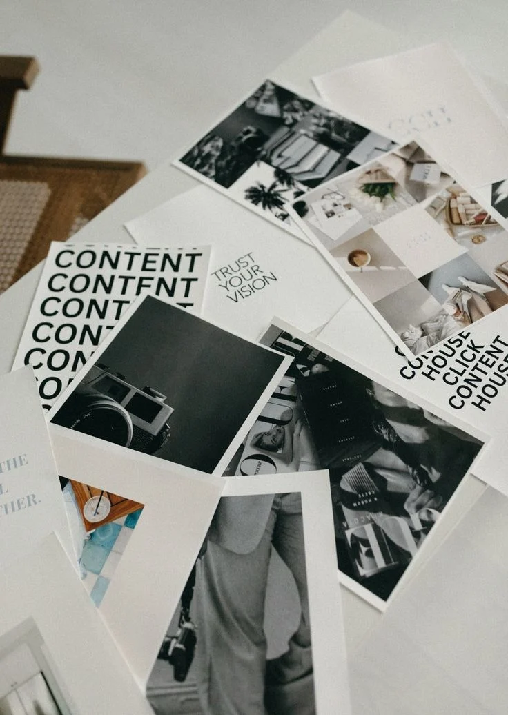 Printed content layouts and photographs spread across a white table
